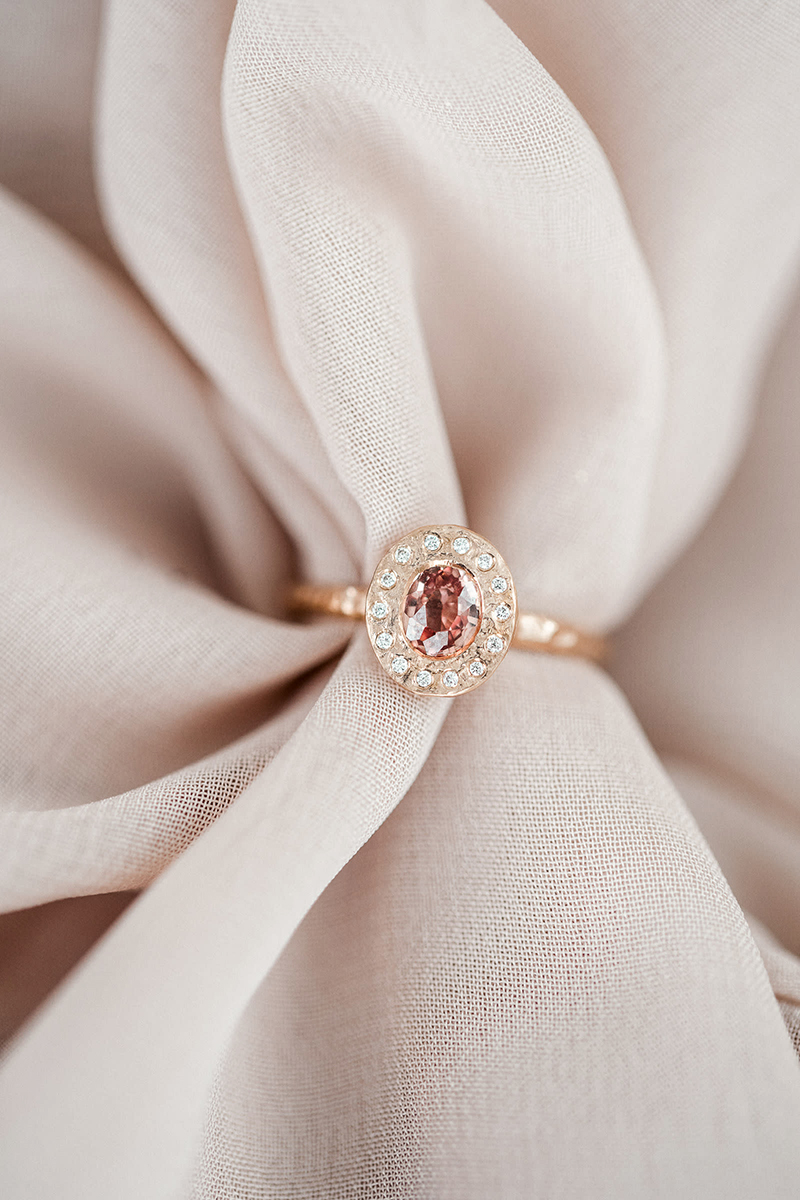 alternative rose gold ring with peach sapphire and halo of diamonds