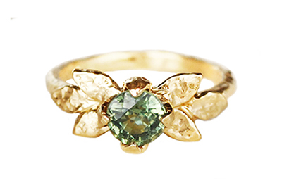 Alternative ring in hammered gold with sculpted leaves and a round green sapphire