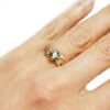 hammered gold leaves with green sapphire alternative engagement ring on a hand
