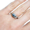 Oval light blue sapphire ring with gold leaves and an accent diamond on hand