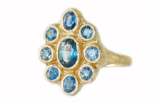 Artisanal hammered gold ring with nine oval and round rustic blue sapphires, made