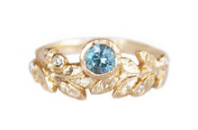 Round teal sapphire ring with accent diamonds and golden leaves