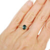 Oval deep teal sapphire ring set in prongs in hammered gold, on hand