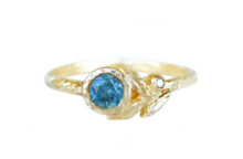 Golden leaf ring with a teal sapphire and accent diamond