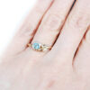 Textured gold ring with leaves, featuring a round teal sapphire and a diamond
