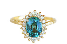 Oval teal sapphire engagement ring with diamond halo, and textured gold