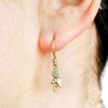 Three leaf gold dangling earrings with aquamarines, shown on ear