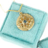 Blue sapphire and diamonds gold mandala medallion necklace on a velvet box