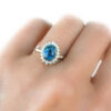 Teal sapphire ring with diamond halo, vintage style rosetta design, on a hand