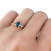 Oval parti blue sapphire set in textured gold ring on a hand
