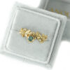 Gold leaves ring with green sapphire and accent diamonds in a velvet ring box