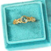 golden leaves ring with accent diamonds and green sapphire, in a velvet ring box
