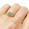 Organic ring with diamonds and green sapphire, on a hand
