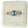 White gold ring with pale rustic blue sapphire and accent diamonds in a vintage velvet ring box
