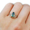 large green pear sapphire ring with golden leaves, on a hand