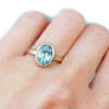 Oval teal sapphire organic gold ring on a hand