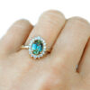Light green-blue sapphire and diamond halo engagement ring in a vintage rosetta style