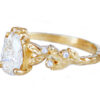 pear shape lab diamond ring with golden leaves and accent diamonds, in profile