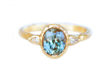 textured gold ring with oval teal sapphire and pear diamond accents