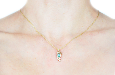 golden pendant with emerald and diamond, worn on a neck