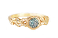 round teal sapphire engagement ring with golden leaves and accent diamonds,