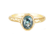 oval teal sapphire engagement ring in textured gold